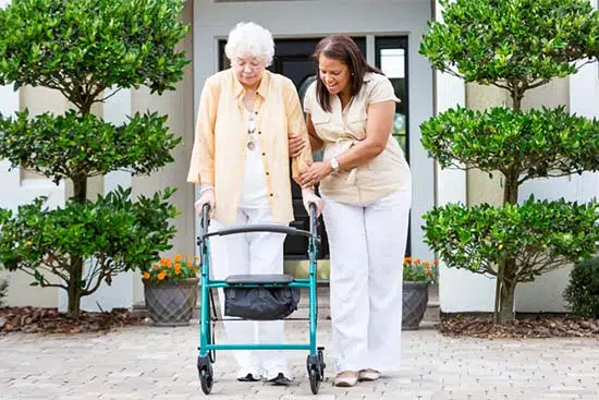 Home Health Aide assists a retired older person with their walker at the Villages of Florida